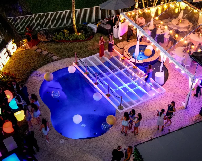 Clear acrylic pool cover dance floor installed for a luxury backyard event with guests enjoying the space