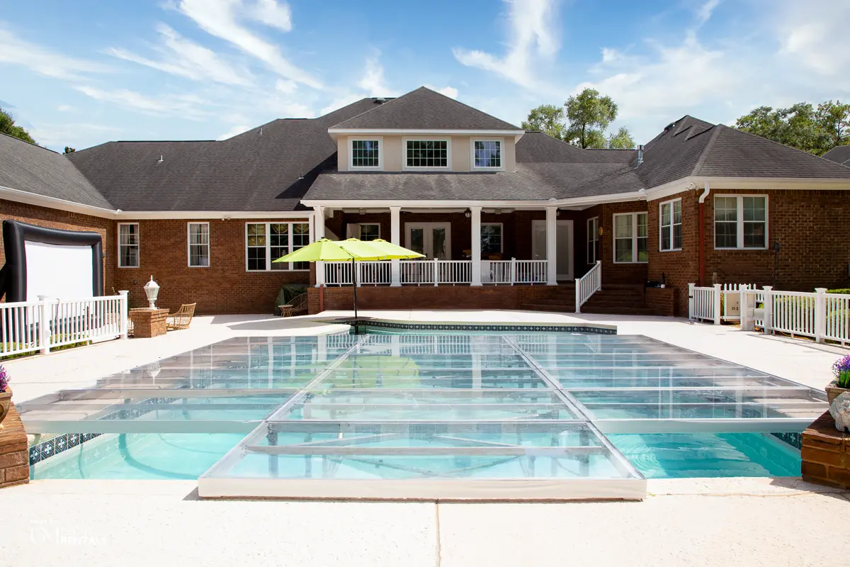 A transparent plexiglass pool cover transforming a backyard pool into an elegant dance floor platform for events